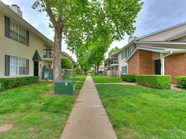 view of community with a yard, fence, and a residential view