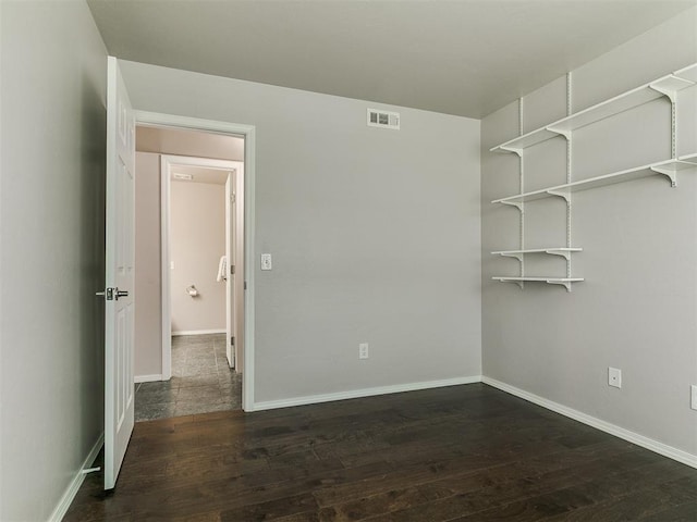 spare room with baseboards, visible vents, and wood finished floors