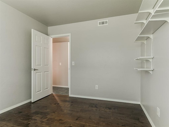 spare room with baseboards, visible vents, and wood finished floors