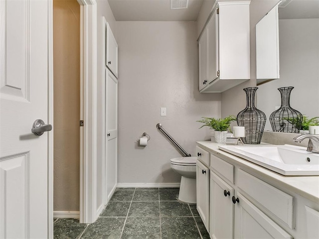 bathroom with vanity, toilet, baseboards, and visible vents