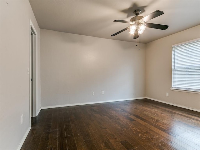 spare room with baseboards, dark wood-style flooring, and ceiling fan