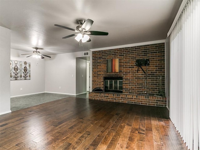 unfurnished living room featuring baseboards, visible vents, ceiling fan, a brick fireplace, and hardwood / wood-style flooring