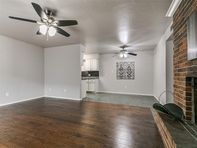 unfurnished living room with baseboards, dark wood-style flooring, a fireplace, and ceiling fan