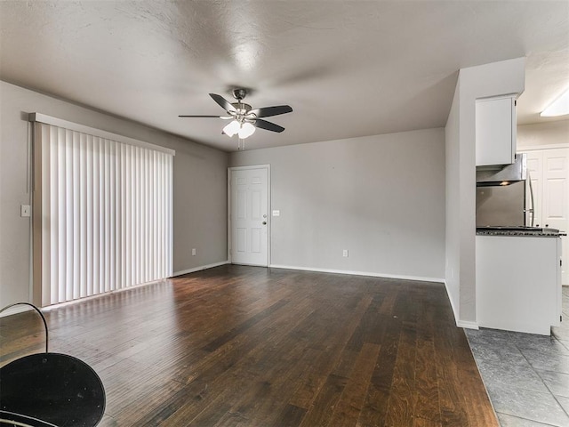 unfurnished living room with a ceiling fan, baseboards, and wood finished floors