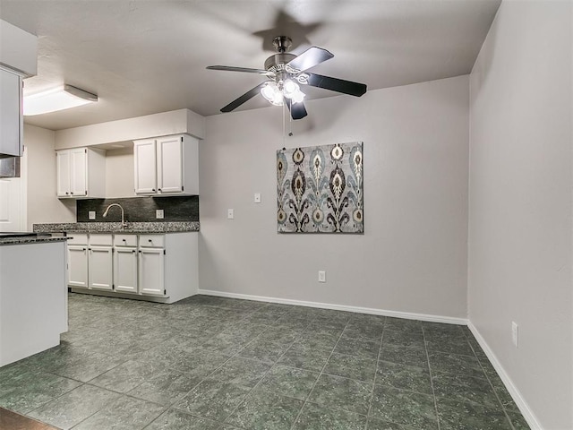 kitchen featuring ceiling fan, backsplash, baseboards, and white cabinets