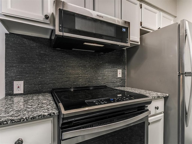 kitchen featuring dark stone counters, decorative backsplash, stainless steel appliances, and white cabinetry