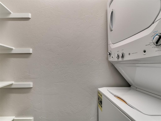 laundry room featuring laundry area, stacked washer and clothes dryer, and a textured wall