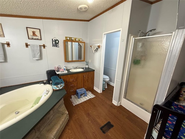 full bath with crown molding, toilet, a shower stall, wood finished floors, and a garden tub