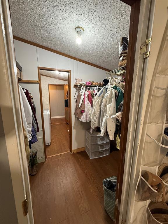 spacious closet featuring vaulted ceiling, wood finished floors, and washer / dryer
