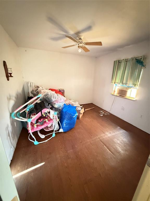 unfurnished bedroom with a ceiling fan, wood finished floors, and cooling unit