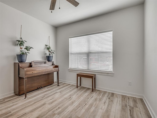 living area featuring baseboards, ceiling fan, and wood finished floors
