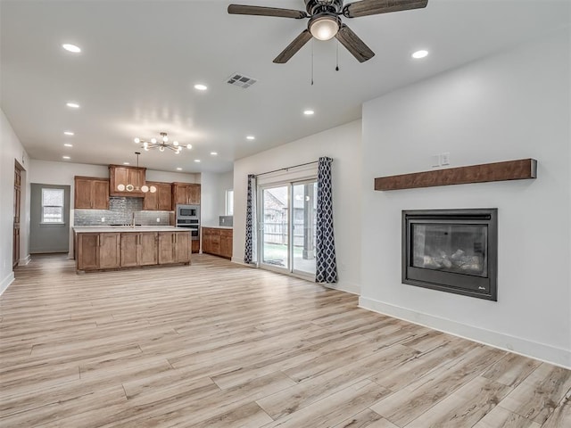 kitchen featuring brown cabinetry, visible vents, open floor plan, recessed lighting, and light countertops