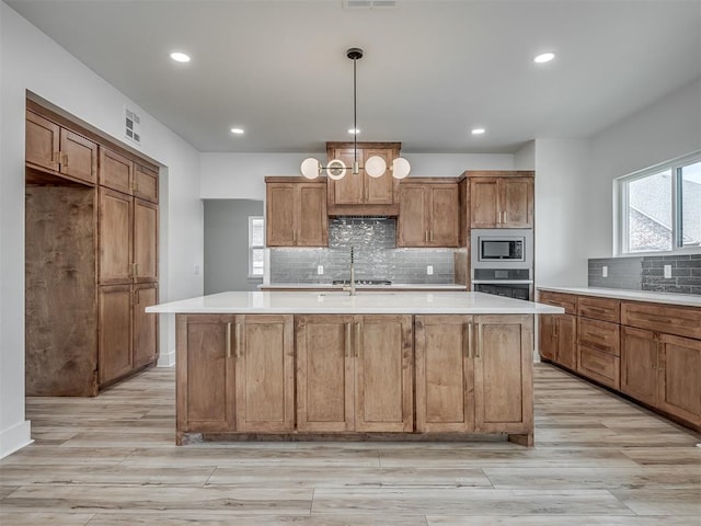 kitchen with brown cabinets, stainless steel appliances, tasteful backsplash, and light countertops