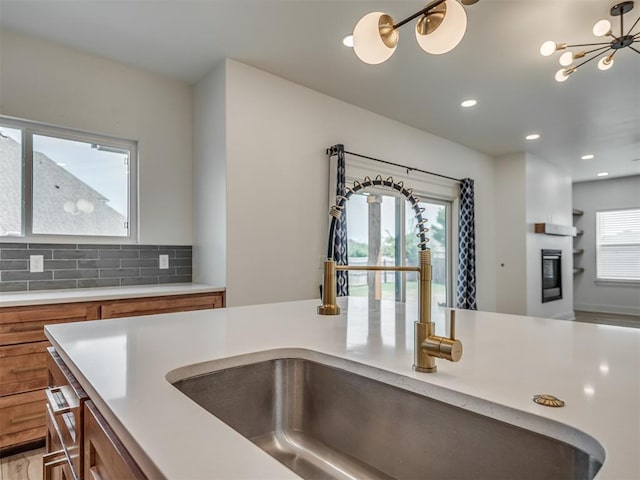 kitchen with brown cabinetry, a sink, and light countertops