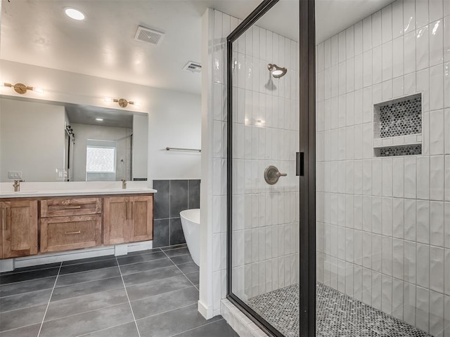 bathroom with visible vents, tile walls, tile patterned floors, a sink, and a stall shower