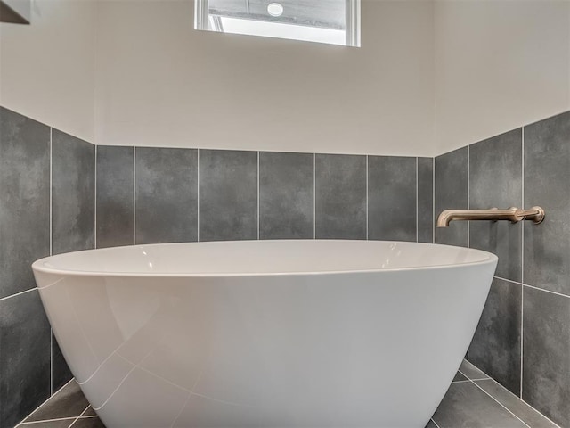 full bath featuring tile patterned floors, tile walls, and a soaking tub