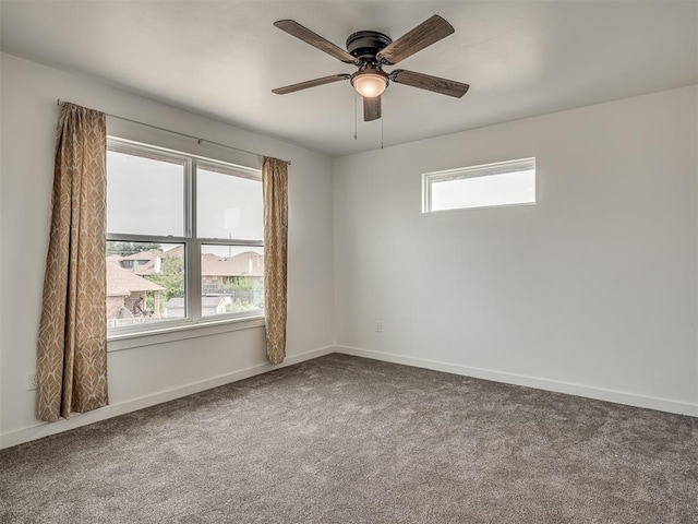 carpeted spare room with a ceiling fan and baseboards