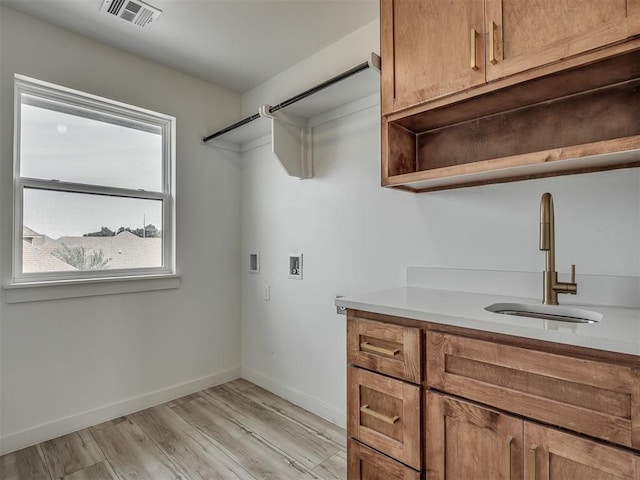 clothes washing area featuring washer hookup, visible vents, cabinet space, a sink, and light wood-style floors
