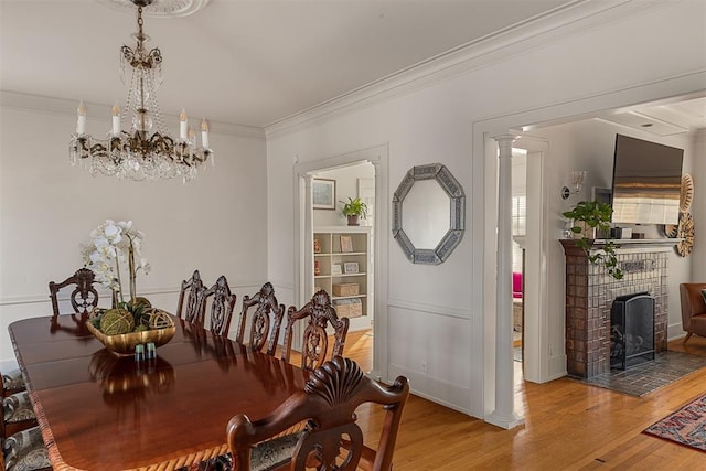 201 NW 18th St, Oklahoma City, OK 73103 - dining room with light wood-type flooring, ornamental molding, a brick fireplace, and a chandelier