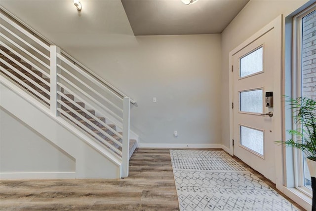 foyer featuring baseboards, light wood-style flooring, and stairway