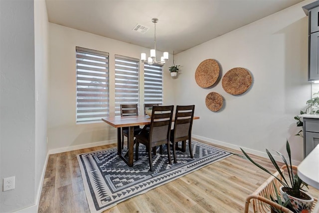 dining room with a chandelier, baseboards, visible vents, and wood finished floors