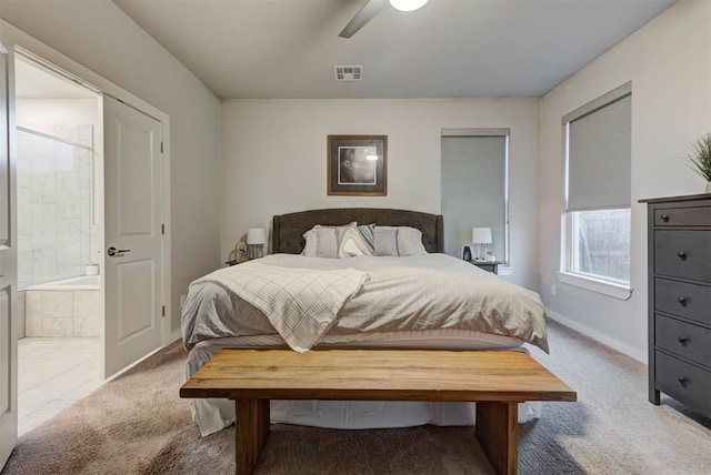 carpeted bedroom featuring baseboards, ceiling fan, ensuite bath, and visible vents