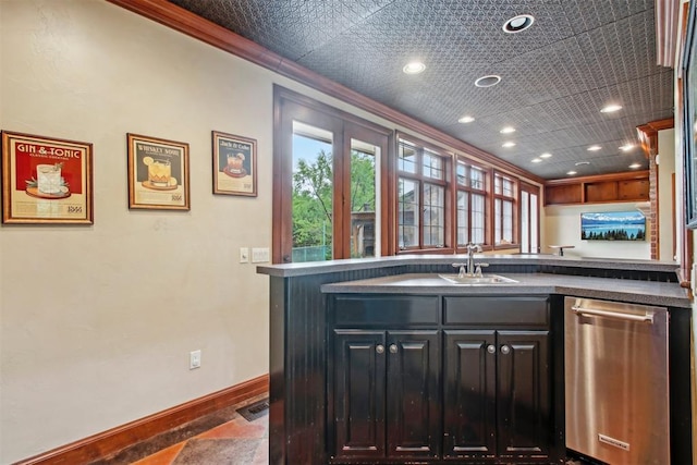 kitchen with ornamental molding, dark countertops, baseboards, a sink, and dishwasher