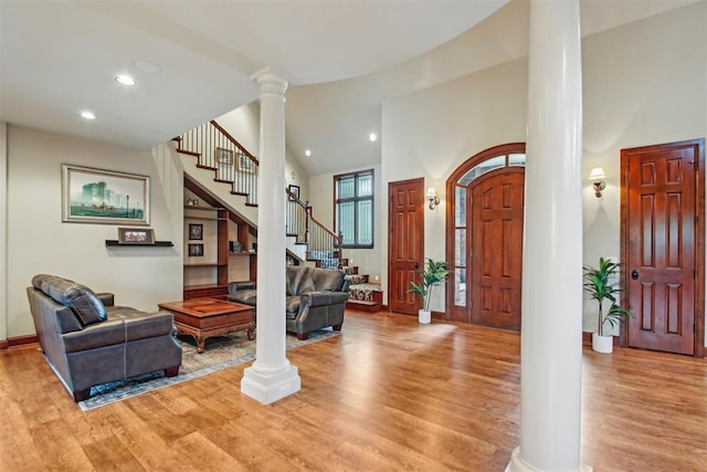 foyer entrance with decorative columns, stairs, wood finished floors, high vaulted ceiling, and recessed lighting