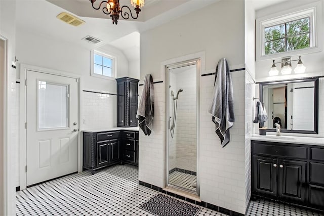 bathroom with visible vents, tile walls, a tile shower, vanity, and a chandelier