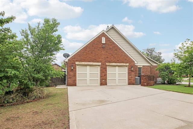 exterior space featuring a garage, concrete driveway, a front lawn, and brick siding
