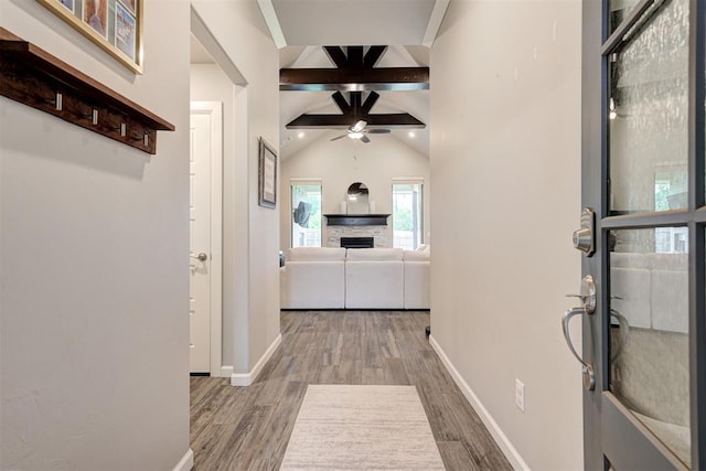 hall with baseboards, lofted ceiling with beams, and wood finished floors