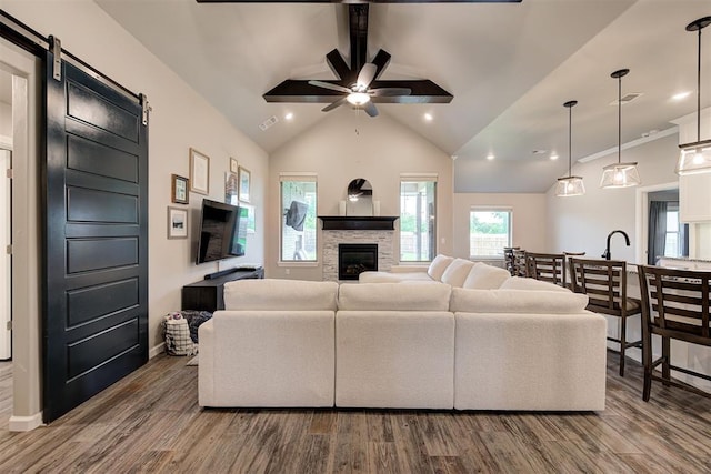 living area with a ceiling fan, lofted ceiling, wood finished floors, and a fireplace