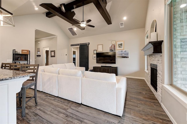 living area featuring visible vents, a barn door, beam ceiling, and a fireplace
