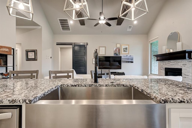 kitchen featuring visible vents, light stone countertops, open floor plan, a barn door, and a sink