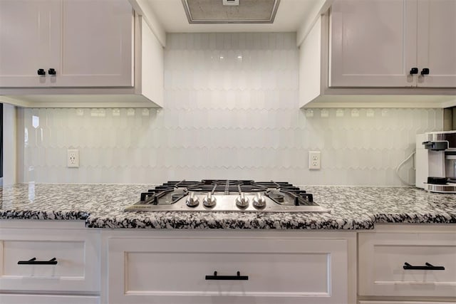 kitchen featuring decorative backsplash, dark stone countertops, and stainless steel gas stovetop