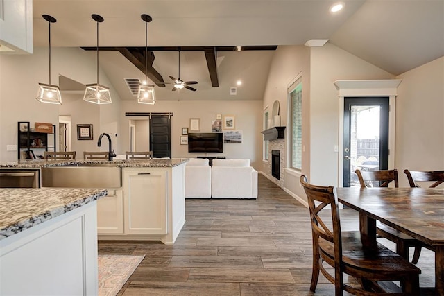 kitchen with white cabinets, light stone counters, a sink, and lofted ceiling