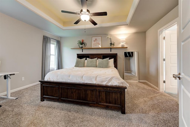 bedroom with a raised ceiling, baseboards, light carpet, and ceiling fan