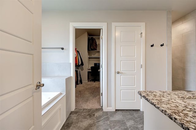 full bath featuring a spacious closet, a garden tub, and vanity
