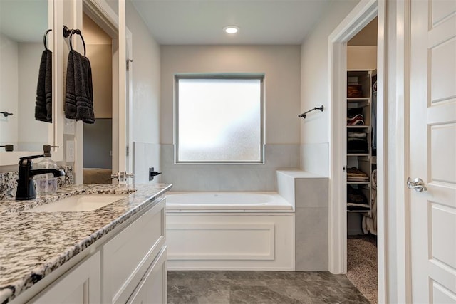 bathroom with vanity, a bath, and a spacious closet