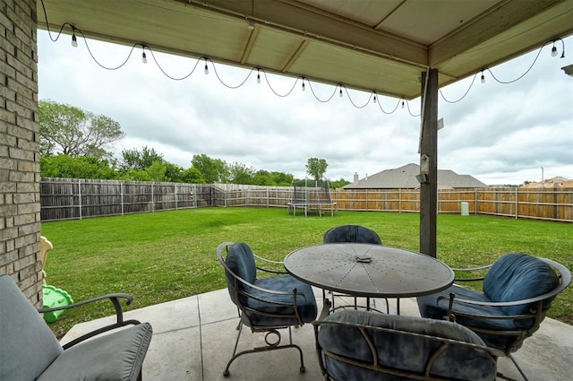 view of patio / terrace featuring a fenced backyard, outdoor dining space, and a trampoline