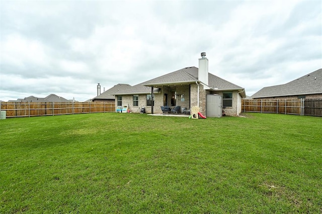 rear view of property with a fenced backyard, a patio area, a yard, and a chimney