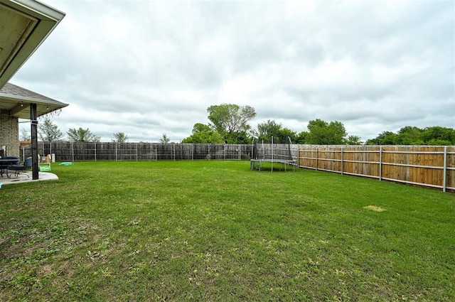 view of yard with a fenced backyard, a trampoline, and a patio