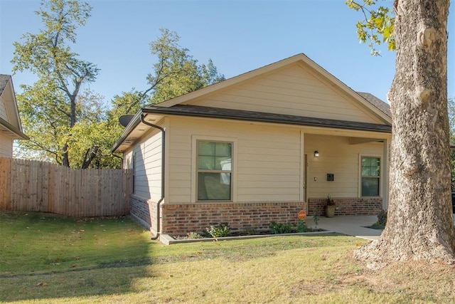 view of front of property with brick siding, a front lawn, and fence