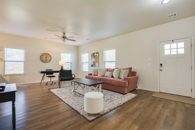 living area featuring ceiling fan, visible vents, plenty of natural light, and dark wood-type flooring