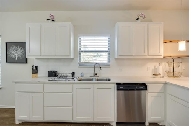 kitchen with stainless steel dishwasher, decorative backsplash, light countertops, white cabinets, and a sink