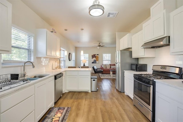 kitchen featuring visible vents, appliances with stainless steel finishes, open floor plan, under cabinet range hood, and white cabinetry