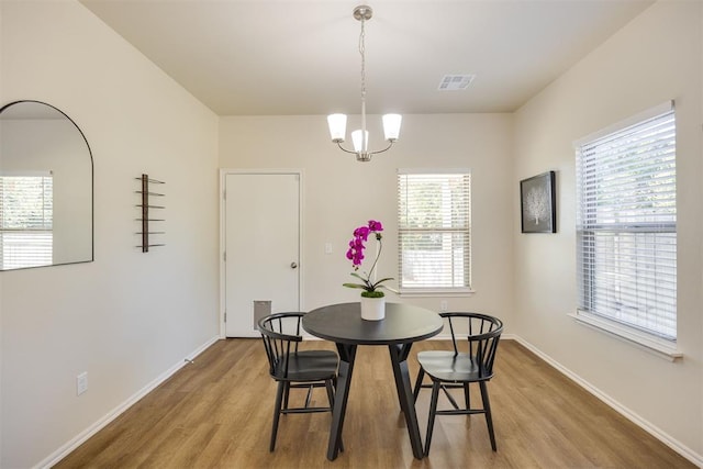 dining room with light wood-style floors, baseboards, a notable chandelier, and visible vents