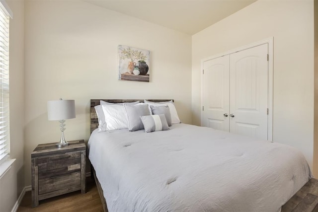 bedroom with baseboards, multiple windows, a closet, and wood finished floors