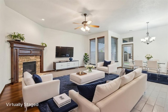 living area featuring ceiling fan with notable chandelier and a fireplace