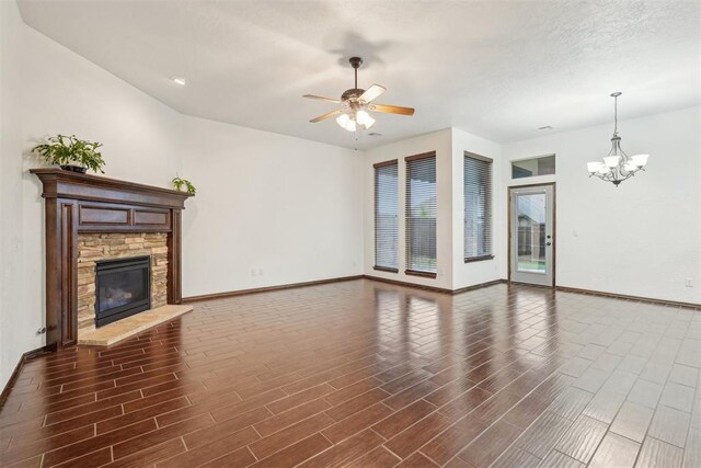 unfurnished living room featuring baseboards, wood finished floors, and ceiling fan with notable chandelier